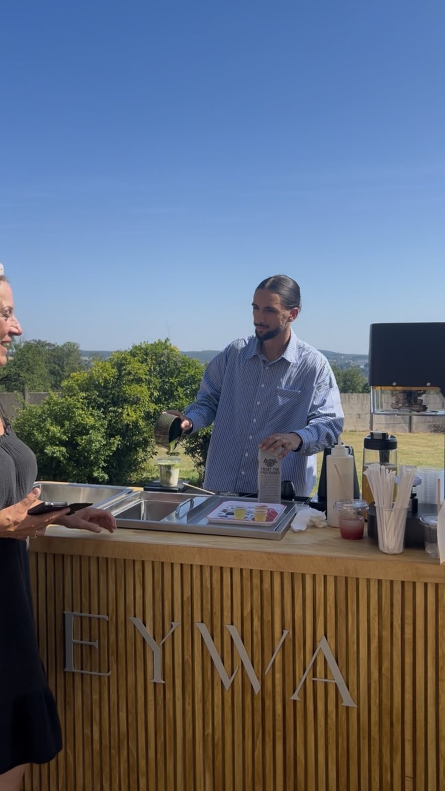 Barista EYWA servant un matcha à une invitée souriante